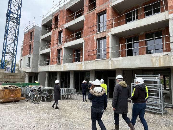 Visite de chantier d’un immeuble de logements à Sainte-Luce-sur-Loire : groupe de professionnels casqués vus de dos et à distance
